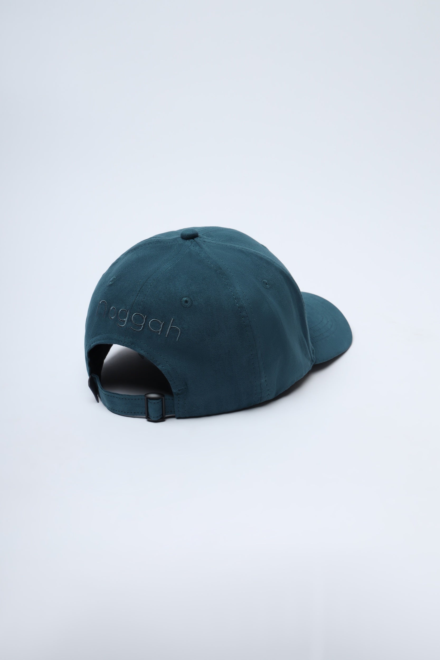 Close-up of bottle green suede cap showing luxury texture and clean branding
