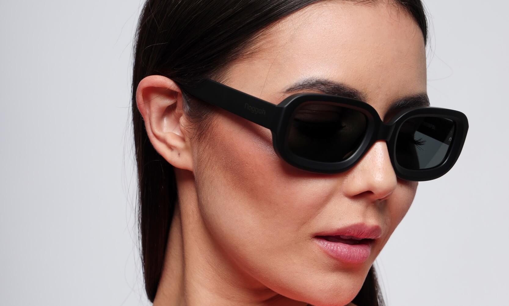 Close-up of Glow Midnight Steel sunglasses (NS1003BFBL) featuring black frame and tempered glass lenses with UV400 protection