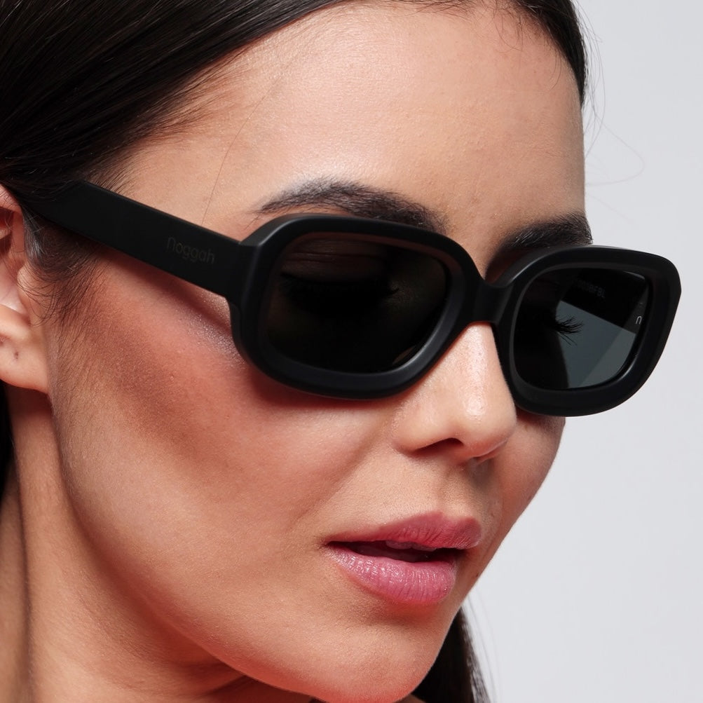 Close-up of Glow Midnight Steel sunglasses (NS1003BFBL) featuring black frame and tempered glass lenses with UV400 protection