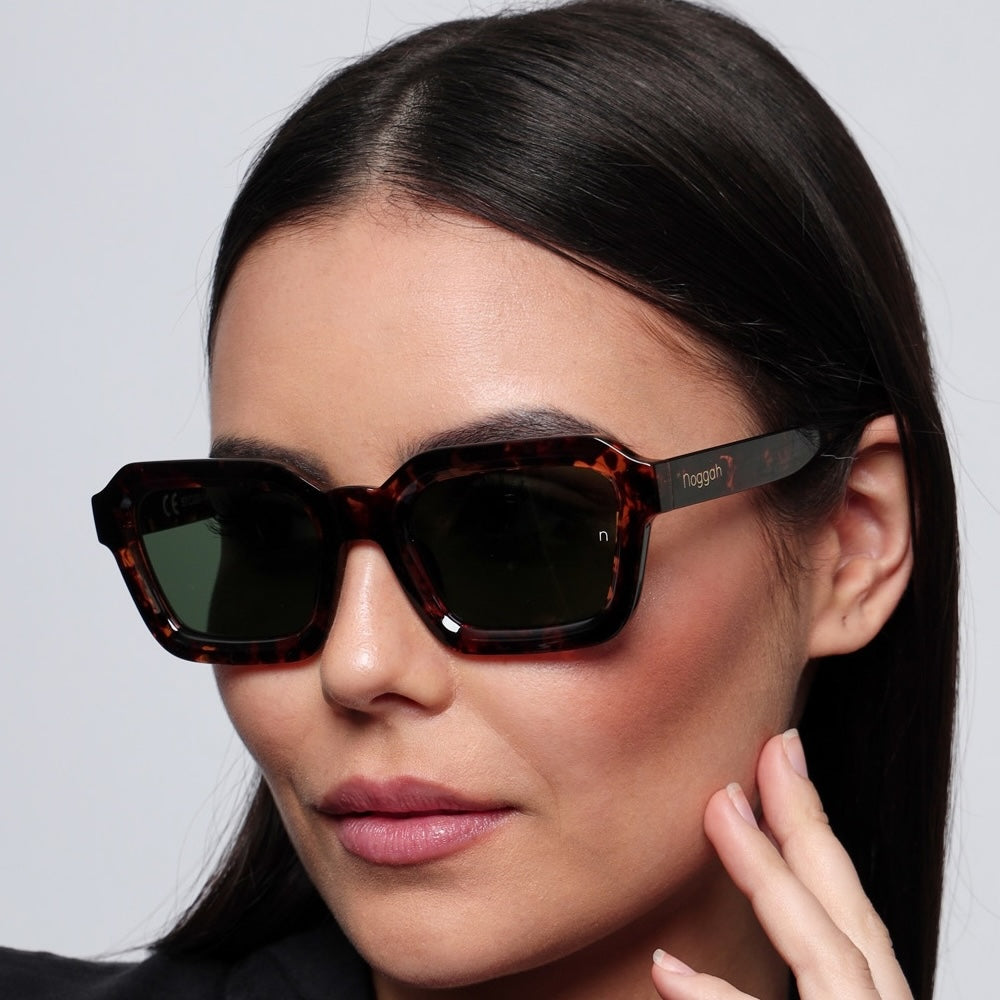 Side profile of Orbit Tortoise Drift sunglasses (NS1007TFGL) with tortoise-shell frame, glass lenses, and a sleek urban backdrop